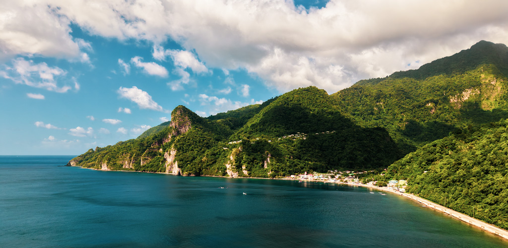 Sunlit west-coast Caribbean Sea and forested hills in dry season — the best time to visit dominica for calmer seas, clearer trails, and steady sunshine.