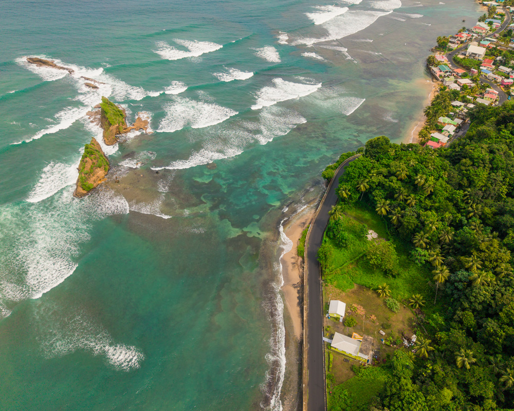 Red cliffs, coconut palms, and Atlantic surf along Calibishie’s shoreline, calibishie dominica’s photogenic north-east village between forest and sea.