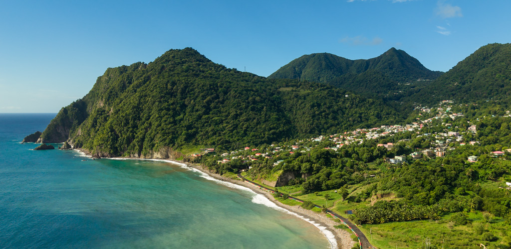 Atlantic surf, fishing boats, and green hills above Berekua (Grand Bay), berekua dominica’s relaxed south-east coastal community facing open ocean.