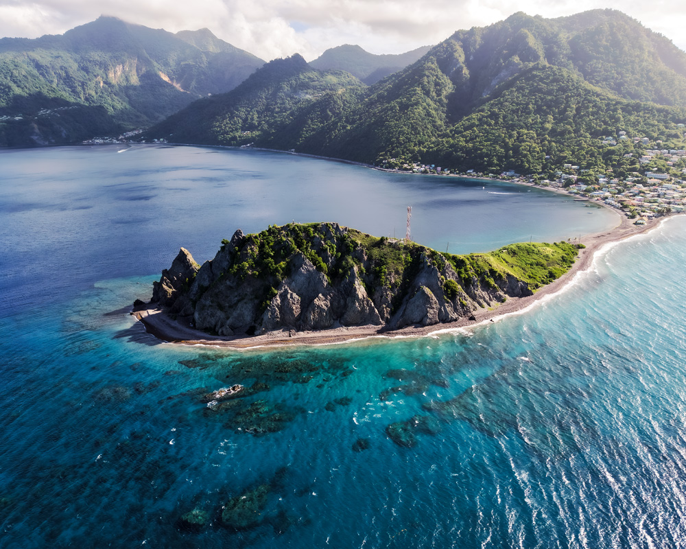 Narrow isthmus at Scotts Head with Caribbean surf west and Atlantic rollers east, scotts head dominica’s iconic southern viewpoint between two seas.