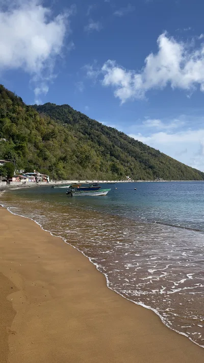 Turquoise Soufrière Bay with small boats moored along the shore, soufriere bay village morning calm before dive boats head out, Dominica.