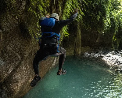 Rope line and life-jacketed visitors wading deeper into the slot, titou gorge swimming progression toward the hidden waterfall chamber, Dominica.